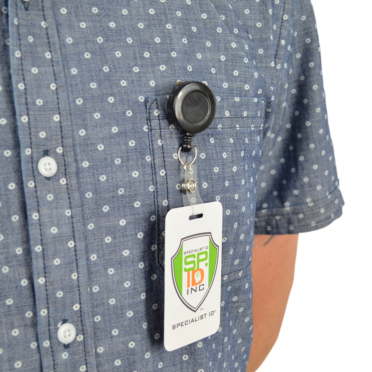 Black retractable badge reel clipped to a shirt pocket with ID badge.