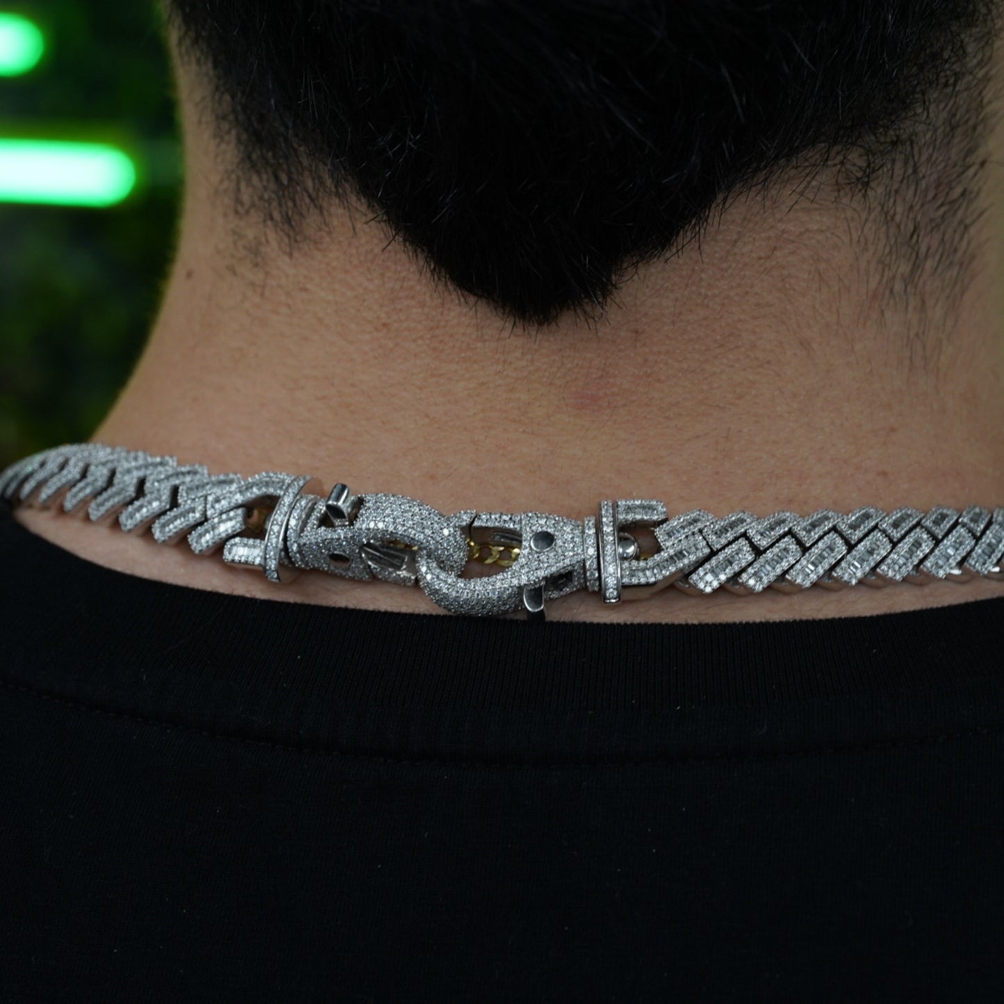 Close-up of diamond-studded clasp on VIP credential chain worn at back of neck