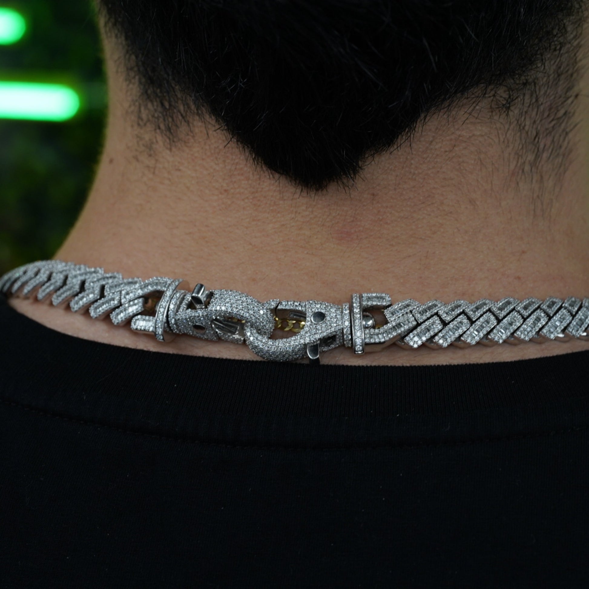 Close-up of diamond-studded clasp on VIP credential chain worn at back of neck