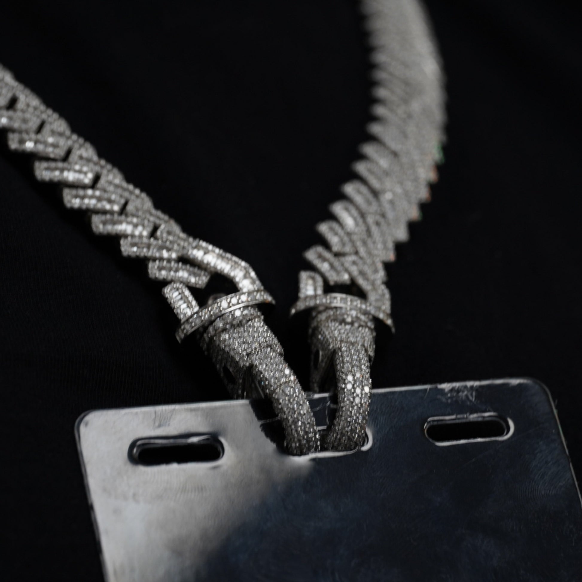 Close-up of diamond-studded connector hooks attaching VIP chain to badge