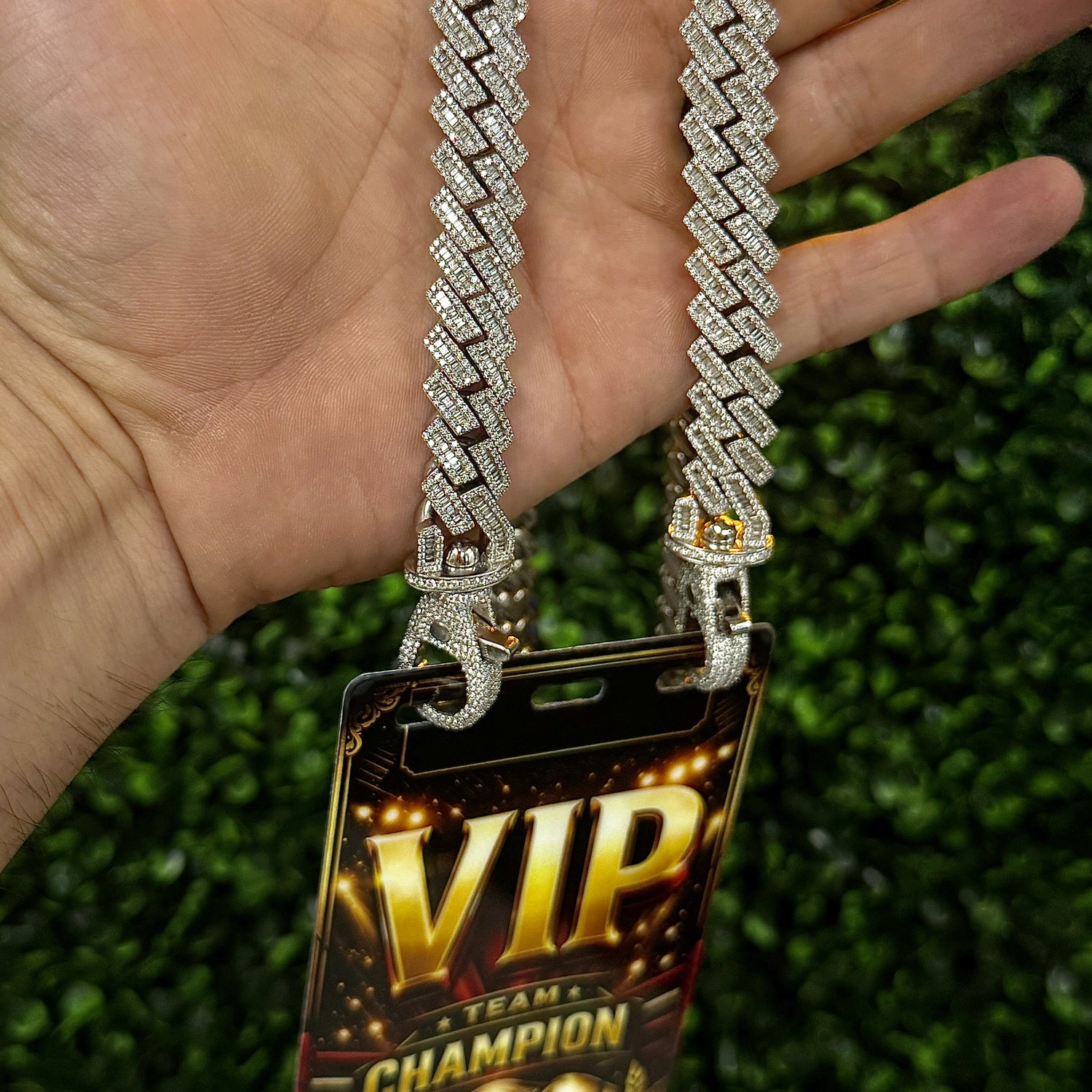 Handheld view of full diamond studded VIP credential chain with badge and clasps visible