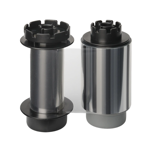 Two cylindrical rolls of film, one with a black and clear body and the other with a shiny silver body, both featuring black end caps, ideal for use with the Evolis RTCL009NAA Clear Transfer Ribbon - 500 Prints, compatible with Avansia Retransfer ID Card Printers.  Sold by Specialist ID, an authorized Evolis dealer.