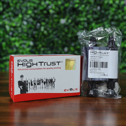 Evolis R3314 YMCKOK Ribbon – 200 prints, shown with branded Evolis High Trust box and sealed twin-spool ribbon package, placed on a wood surface with a blurred green background. Photographed and sold by Specialist ID, an authorized Evolis dealer.