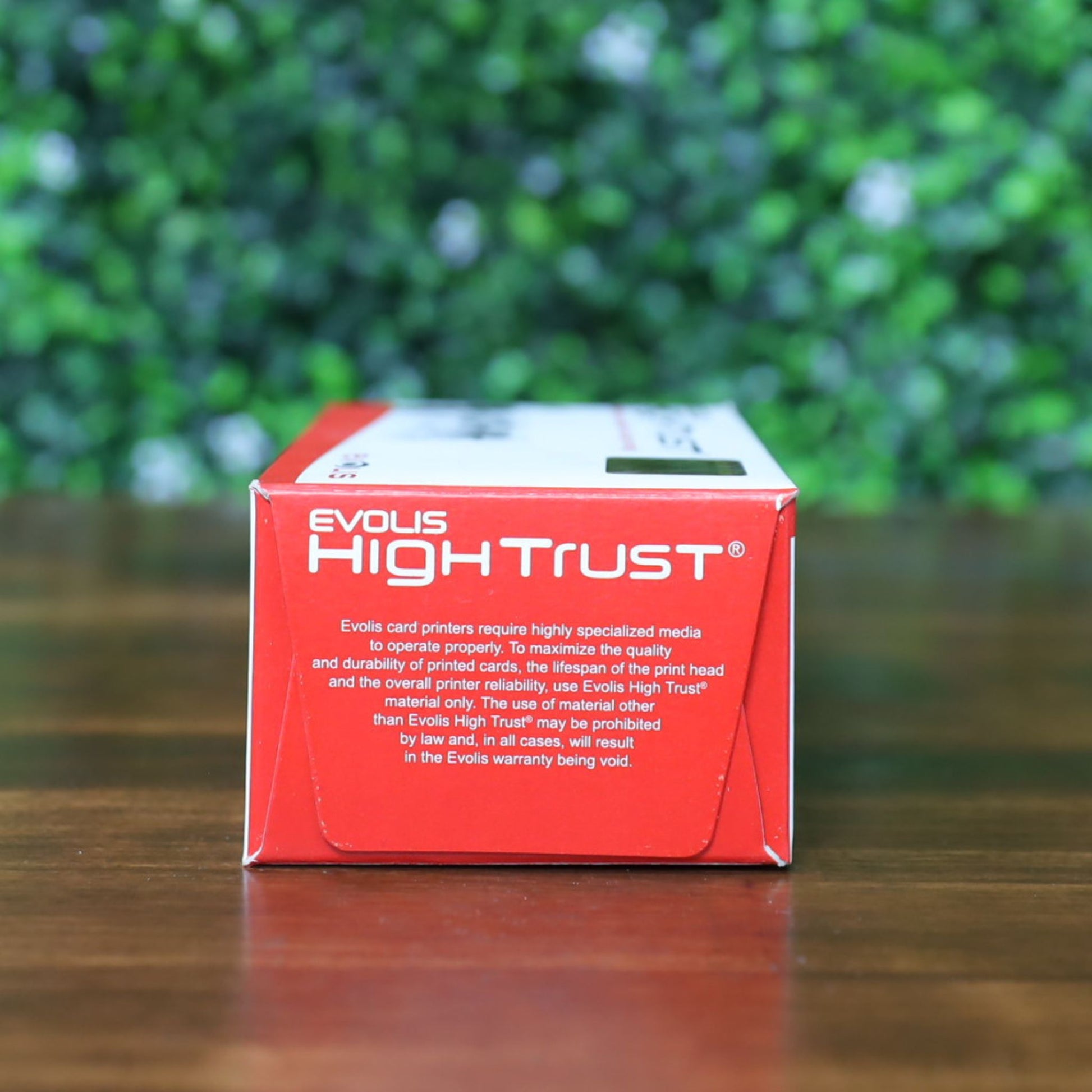 Straight-on view of the Evolis High Trust R3314 YMCKOK Ribbon box displaying the red end panel upright, featuring white High Trust branding and warranty instructions. Photographed and sold by Specialist ID, an authorized Evolis dealer.