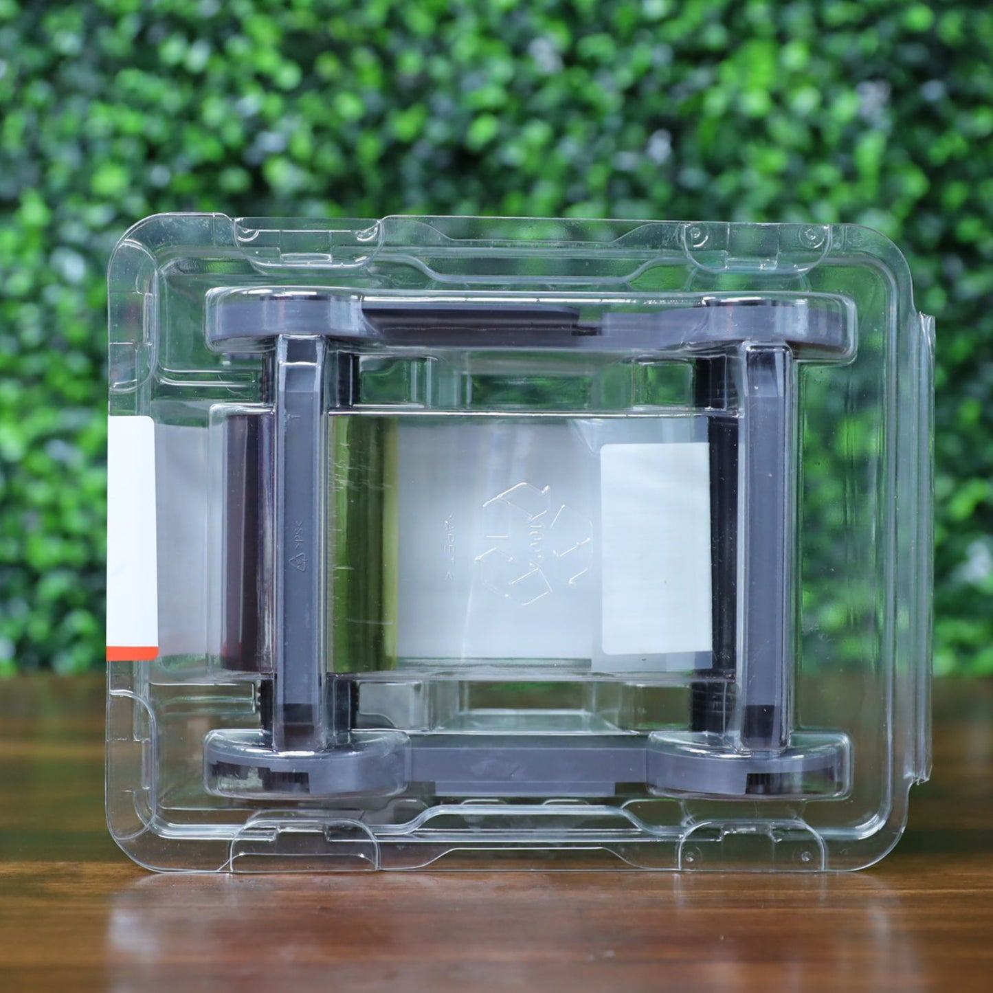 Back view of the Evolis R6F203A100 YMCKO-K ribbon showing the reverse side of the color panels through the transparent clamshell packaging, with visible recyclable symbol embossed on the film. Photographed and sold by Specialist ID, an authorized Evolis dealer.