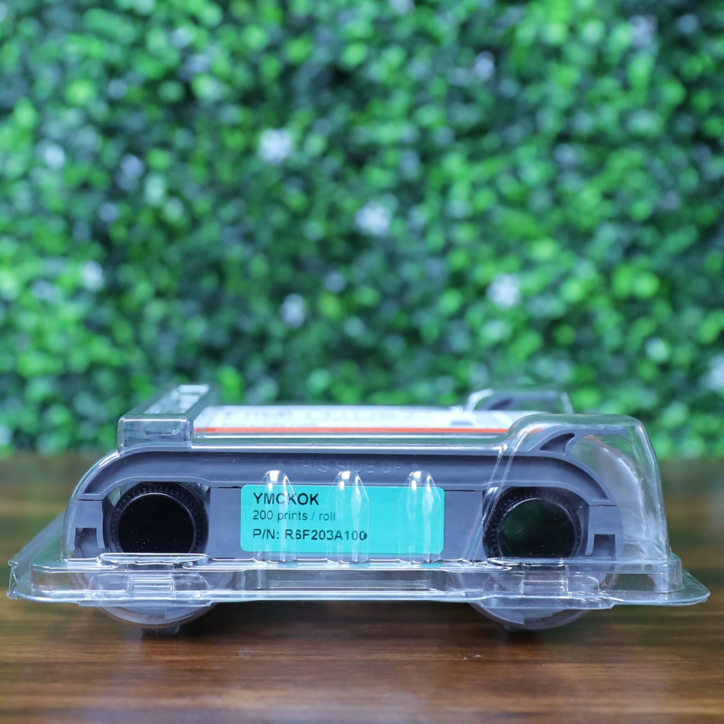 Bottom view of the Evolis R6F203A100 YMCKO-K ribbon showing the model number label with print yield of 200 prints per roll, facing upward inside sealed packaging. Photographed and sold by Specialist ID, an authorized Evolis dealer.