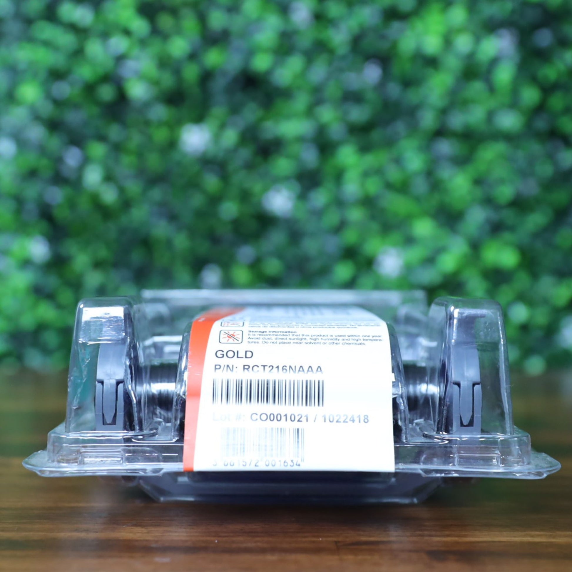 Back view of Evolis RCT216NAAA metallic gold monochrome ribbon in sealed clamshell packaging, showing barcode, lot number CO0001021, and P/N: RCT216NAAA label. Photographed and sold by Specialist ID, an authorized Evolis dealer.