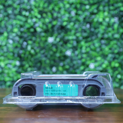 Front-facing view of the Evolis RCT216NAAA gold monochrome ribbon in retail packaging, displaying green label with 'GOLD, Up to 1000 prints / roll, P/N: RCT216NAAA'. Photographed and sold by Specialist ID, an authorized Evolis dealer.