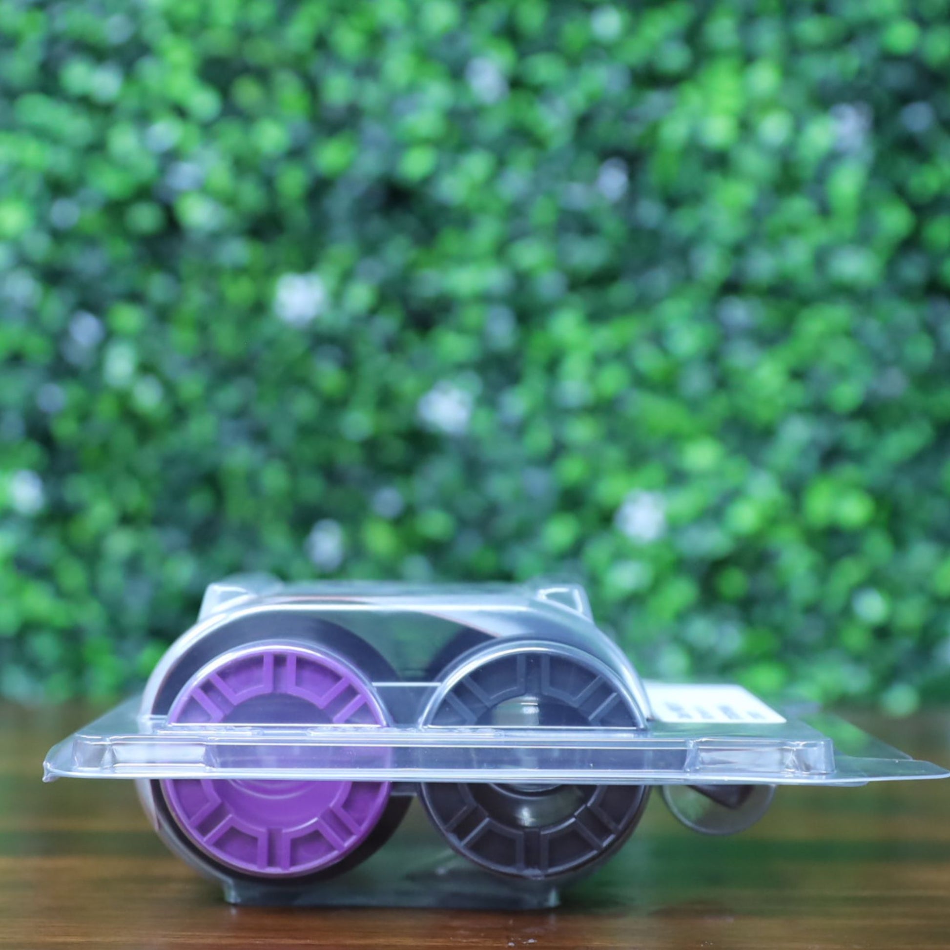 Bottom view of the Evolis RT4F010AAA YMCK ribbon inside sealed High Trust clamshell packaging, highlighting the purple and black spool bases. Photographed and sold by Specialist ID, an authorized Evolis dealer.