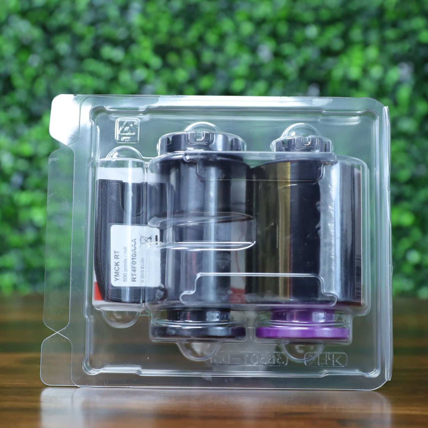 Side-angled view of the Evolis RT4F010AAA YMCK ribbon in sealed clamshell packaging, showing labeled cartridge and color panel spools. Photographed and sold by Specialist ID, an authorized Evolis dealer.