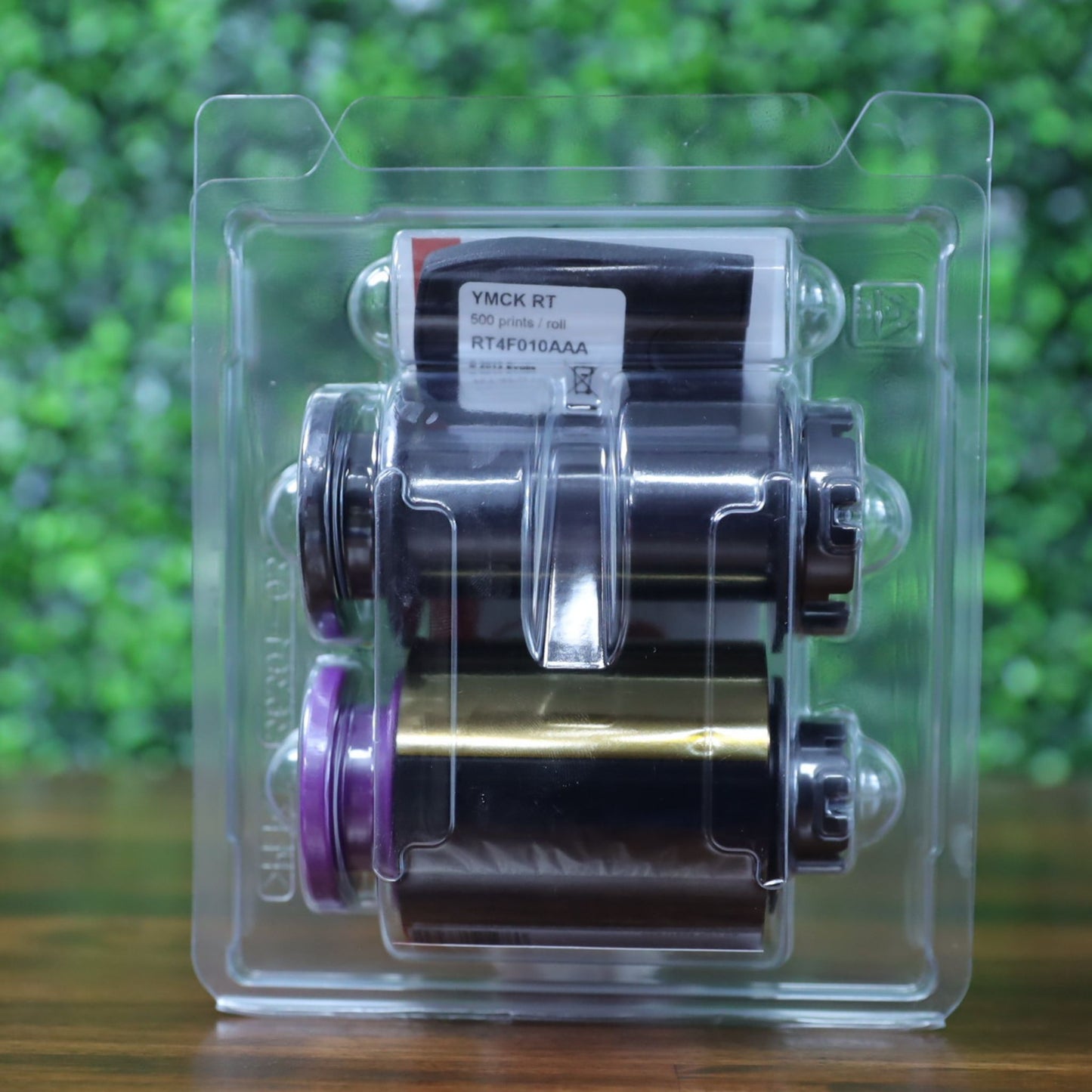Back view of the Evolis RT4F010AAA YMCK ribbon inside its transparent clamshell packaging, clearly displaying product label and dual spool assembly. Photographed and sold by Specialist ID, an authorized Evolis dealer.