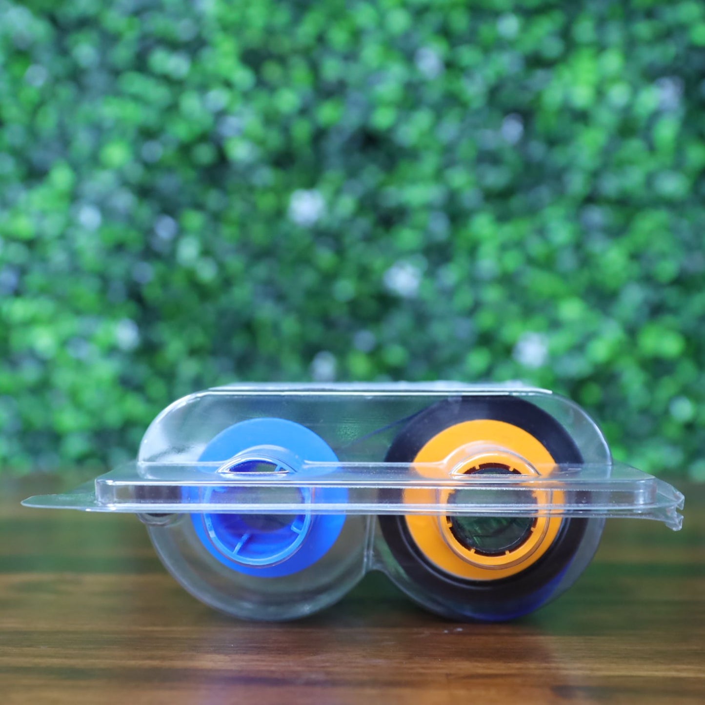 Bottom view of the Fargo 45611 YMCKOK printer ribbon highlighting the colorful blue and orange spool hubs inside the clear plastic casing. Photographed and sold by Specialist ID, an authorized Fargo dealer.