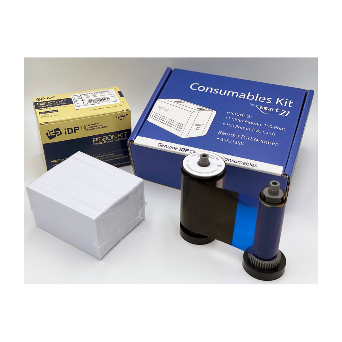 SMART-21 Consumables Kit box listing 1 color ribbon (100-print) and 100 Primus PVC cards, beside the ribbon and a stack of white cards