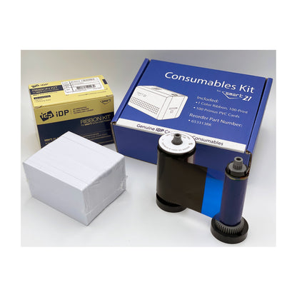 SMART-21 Consumables Kit box listing 1 color ribbon (100-print) and 100 Primus PVC cards, beside the ribbon and a stack of white cards