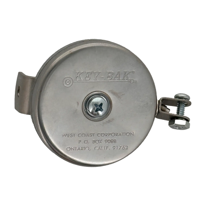 The Key-Bak #481LS-HD Mountable Retractable Reel, featuring a round, silver design with the brand name "KEY-BAK" and manufacturer details engraved on the front, includes a steel cable and comes with an L bracket and hex nut yoke. This heavy-duty key reel is ideal for industrial applications.