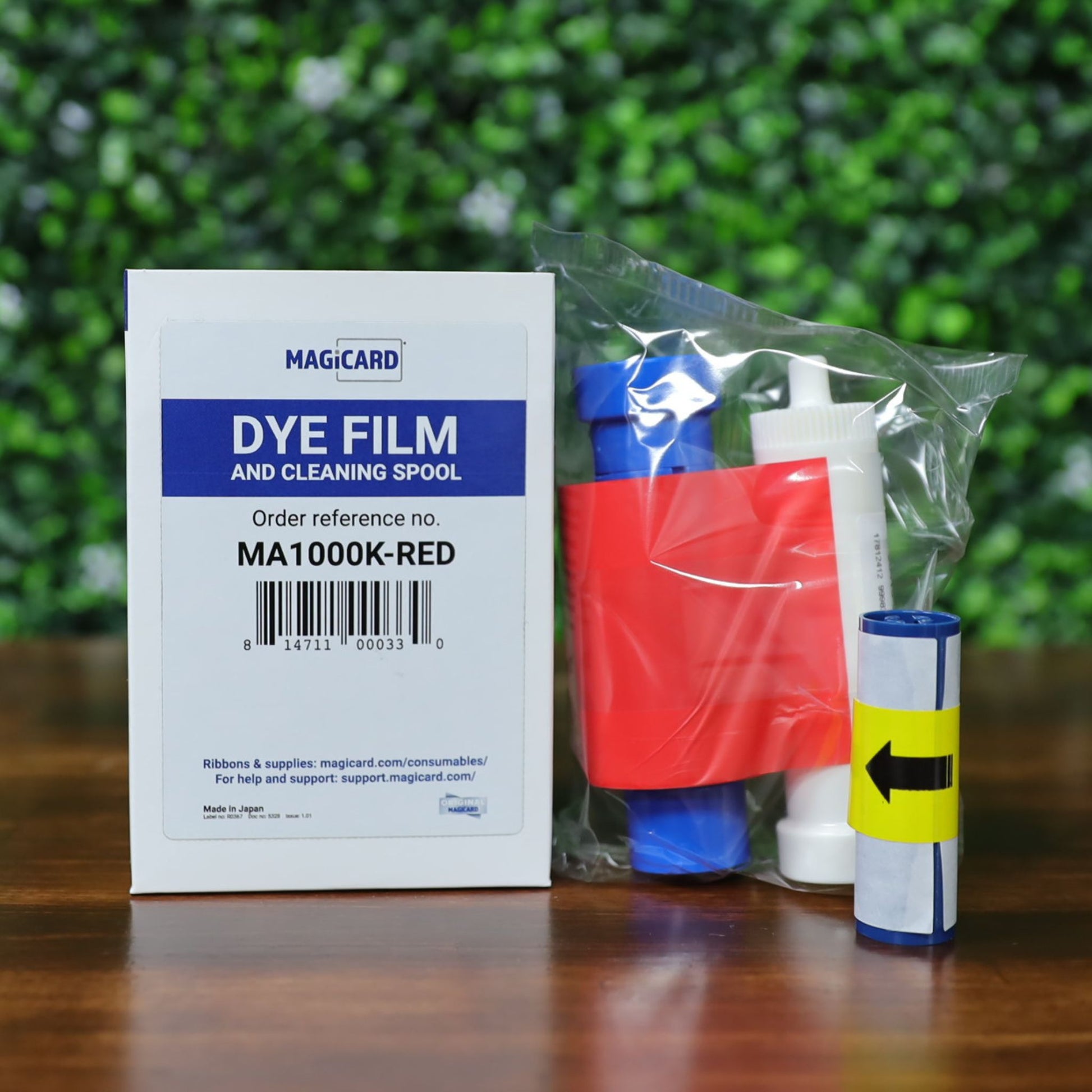Magicard MA1000K-RED red monochrome dye film ribbon with cleaning spool and adhesive roller, photographed in front of box packaging. Photographed and sold by Specialist ID, an authorized Magicard dealer.