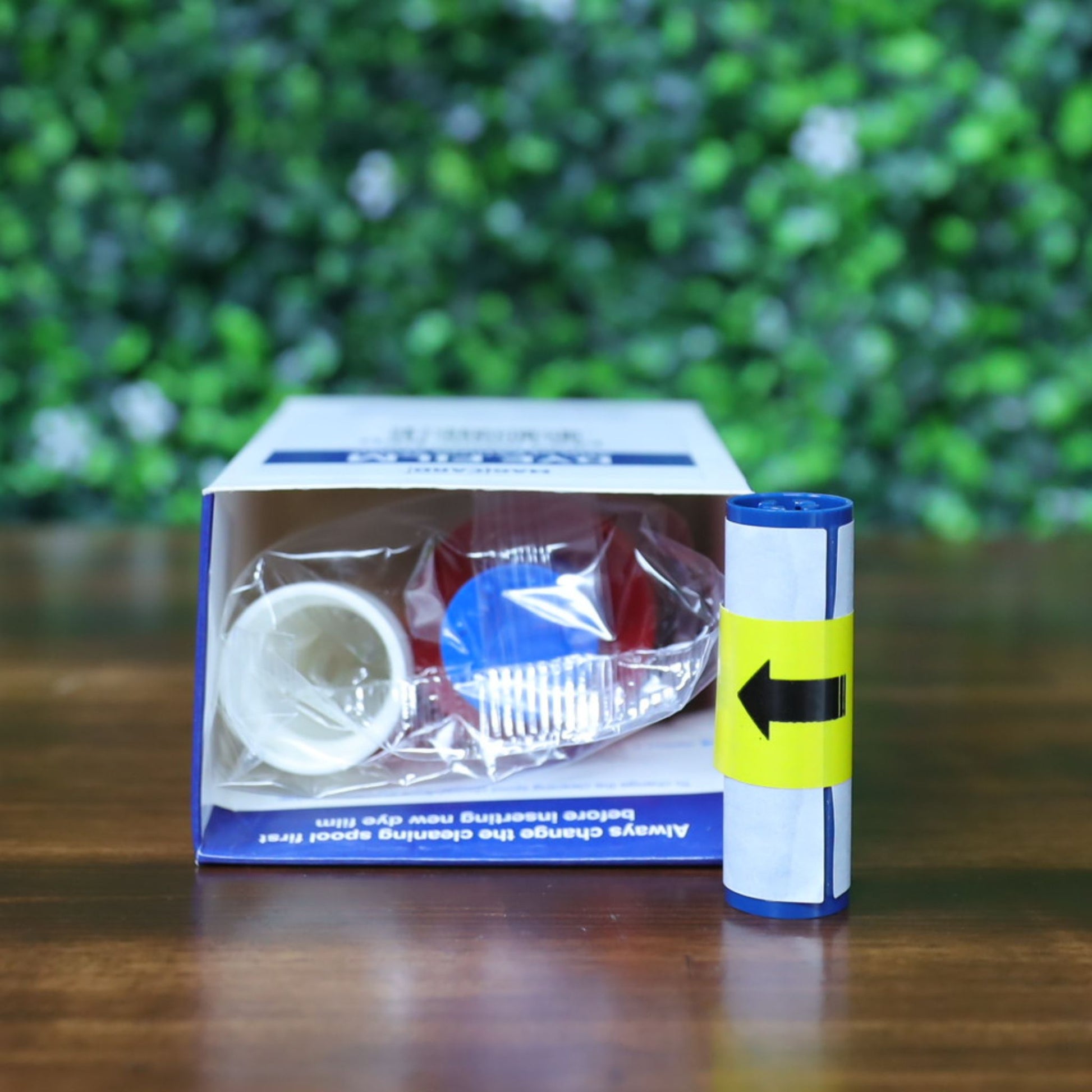 Top-down view of the Magicard MA1000K-RED red monochrome ribbon inside its box, showing the sealed ribbon, white cleaning spool, and adhesive roller. Photographed and sold by Specialist ID, an authorized Magicard dealer.