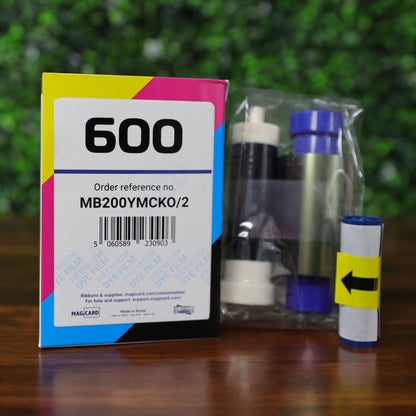 Magicard MB200YMCKO/2 YMCKO ribbon with packaging and contents shown – includes color ribbon, take-up spool, and labeled box for Magicard 600. Photographed and sold by Specialist ID, an authorized Magicard dealer.