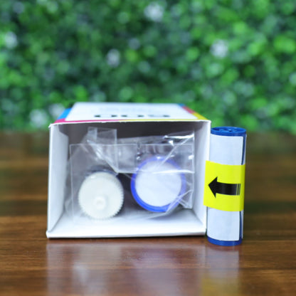 Magicard MB200YMCKO/2 YMCKO ribbon shown partially unboxed with open top flap revealing take-up spool and sealed contents, plus separate ribbon roll with install arrow. Photographed and sold by Specialist ID, an authorized Magicard dealer.