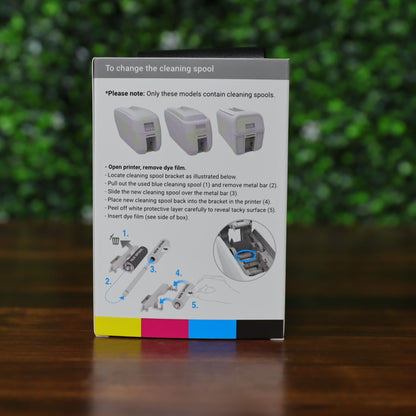 Box of Magicard MB250YMCKOK Color Ribbon (250 prints), compatible with the Magicard 600 ID Card Printer, featuring clear diagrams and text instructions for replacing the ribbon, shown against a blurred background. Photographed and sold by Specialist ID, an authorized Magicard dealer.