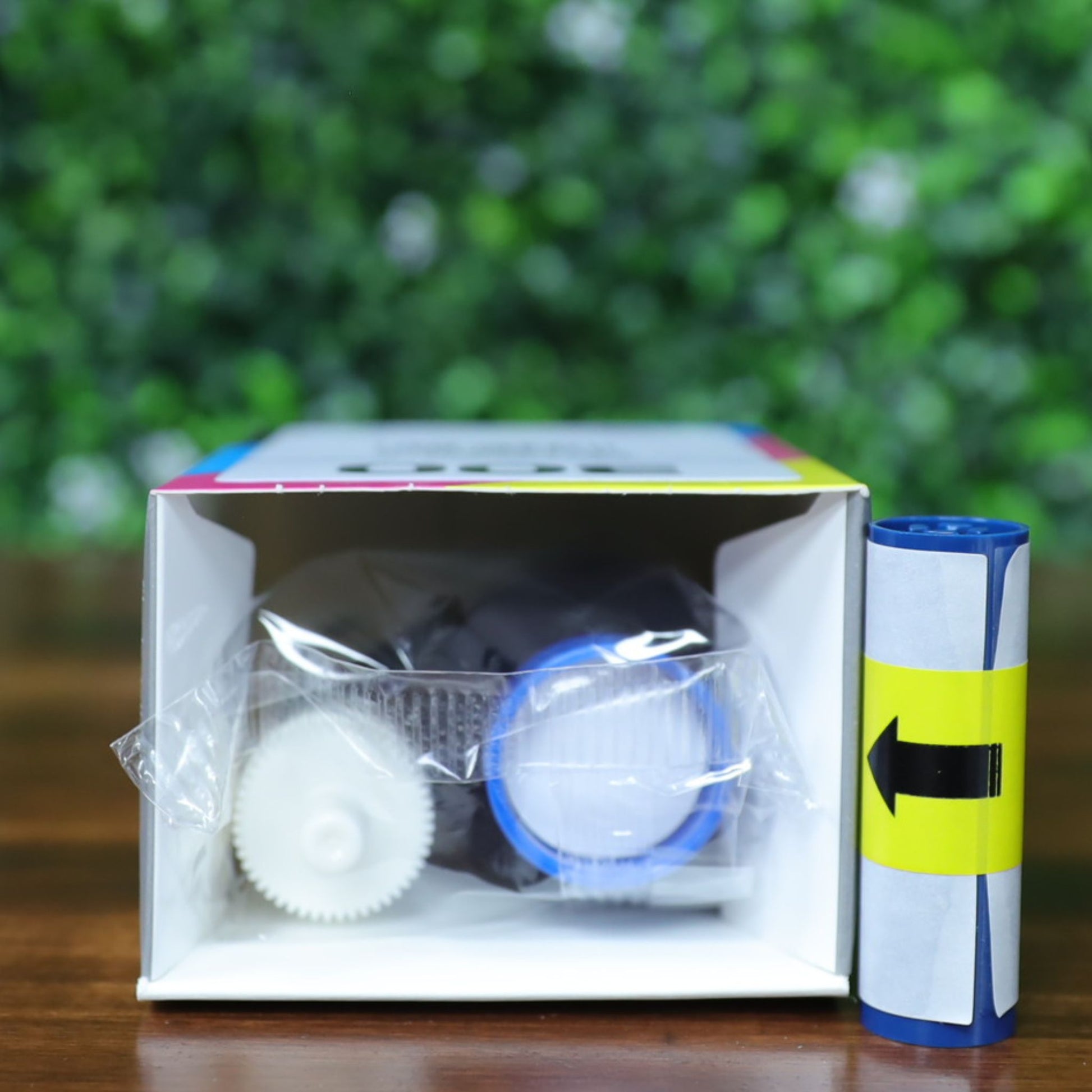 Top-down view of the Magicard MC600KO/2 ribbon and cleaning roller kit as packaged inside the box. The box is lying down and open, showing the sealed KO ribbon with blue and white spools and a separate blue cleaning roller with yellow label placed next to the opening.
Photographed and sold by Specialist ID, an authorized Magicard dealer.