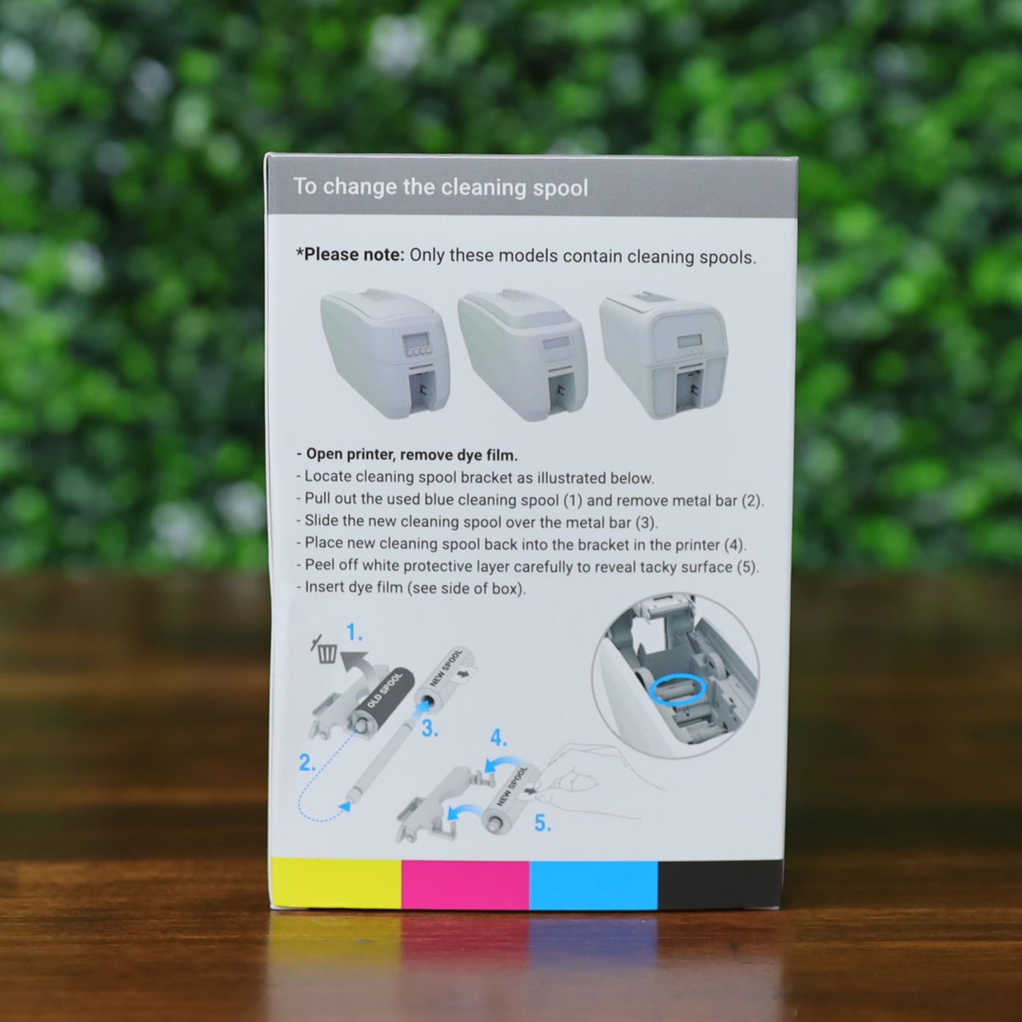Back of the Magicard MD100YMCKO ribbon box showing step-by-step visual instructions for changing the cleaning spool in Magicard Pronto100 printers. Features diagrams, model images, and a color-coded print strip. Photographed and sold by Specialist ID, an authorized Magicard Dealer.