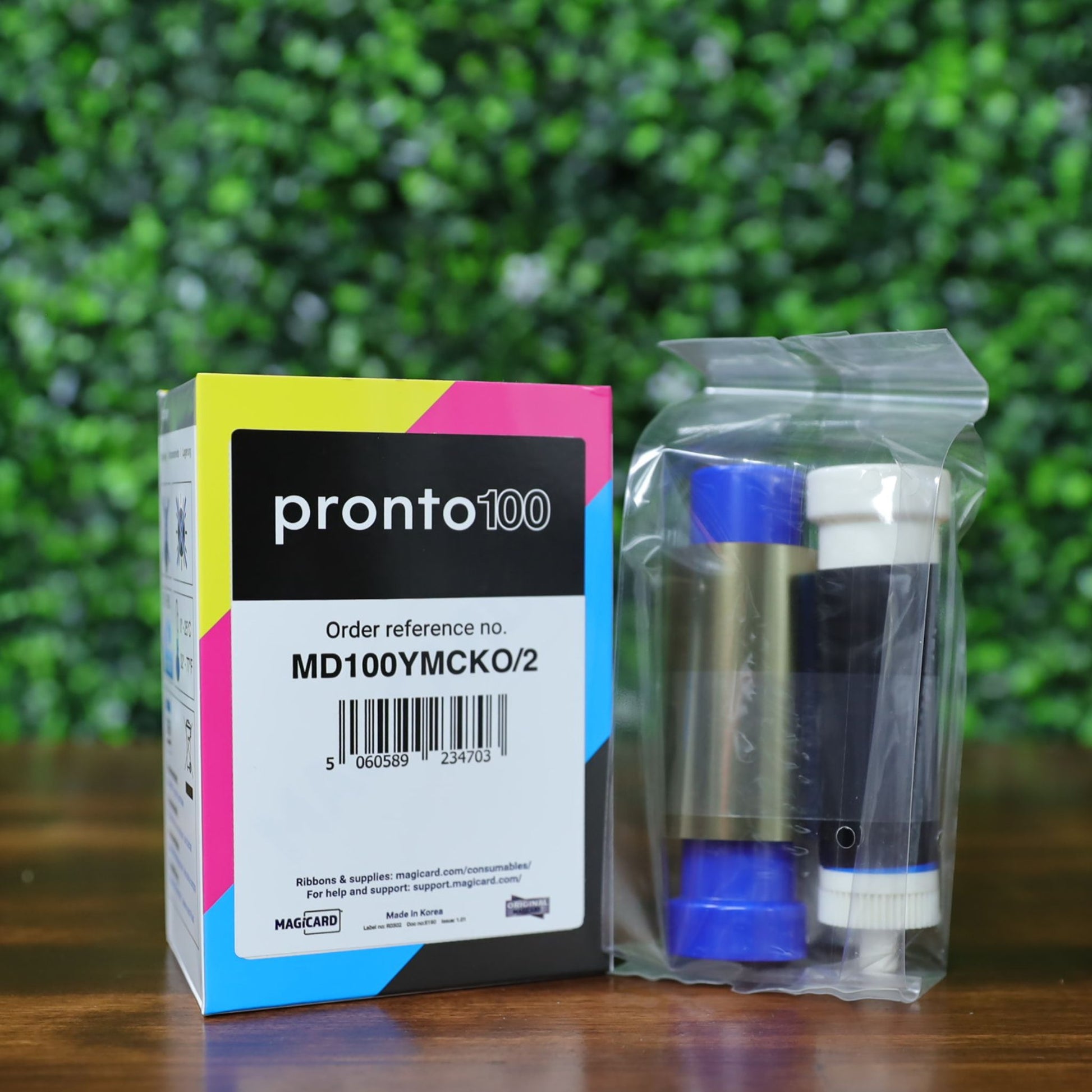 Magicard MD100YMCKO Ribbon photographed next to its official retail box. Includes Pronto100 branding, barcode, and part number MD100YMCKO/2. Ribbon is sealed in factory plastic. Photographed and sold by Specialist ID, an authorized Magicard Dealer.