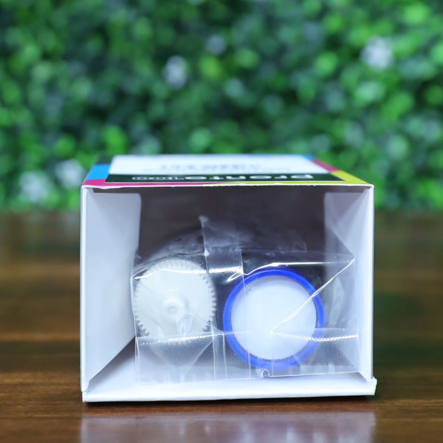 Top-down view of the Magicard MD100YMCKO ribbon box lying flat with the Pronto100 branding visible. Internal ribbon spools are visible through the open flap in sealed packaging. Photographed and sold by Specialist ID, an authorized Magicard Dealer.