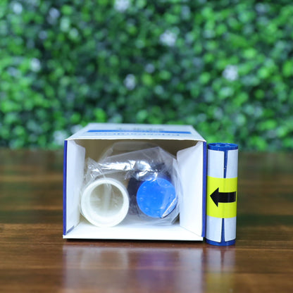 An open box on a wooden surface contains small plastic items and a blue container, with a Magicard PR1000GL Monochrome Gold Ribbon—1000 prints, compatible with PriceCardPro 100 and Flex+ ID card printers—beside it. The background has a green leafy pattern. Photographed and sold by Specialist ID, an authorized Magicard dealer.