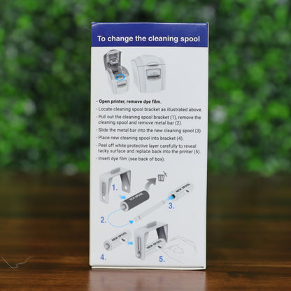 Side panel of the Magicard PR1000W monochrome ribbon box showing step-by-step cleaning spool replacement instructions. Diagram includes numbered illustrations for removing the old spool and inserting a new one using the included metal bar. Blue directional arrows guide the process. Photographed and sold by Specialist ID, an authorized Magicard dealer.