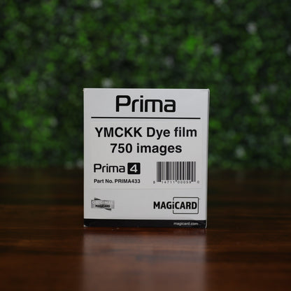 Magicard Prima433 YMCKK Ribbon box for 750 dual-sided ID card prints, shown with barcode and Magicard branding on a wooden surface against a green leafy backdrop. Photographed and sold by Specialist ID, an authorized Magicard dealer.