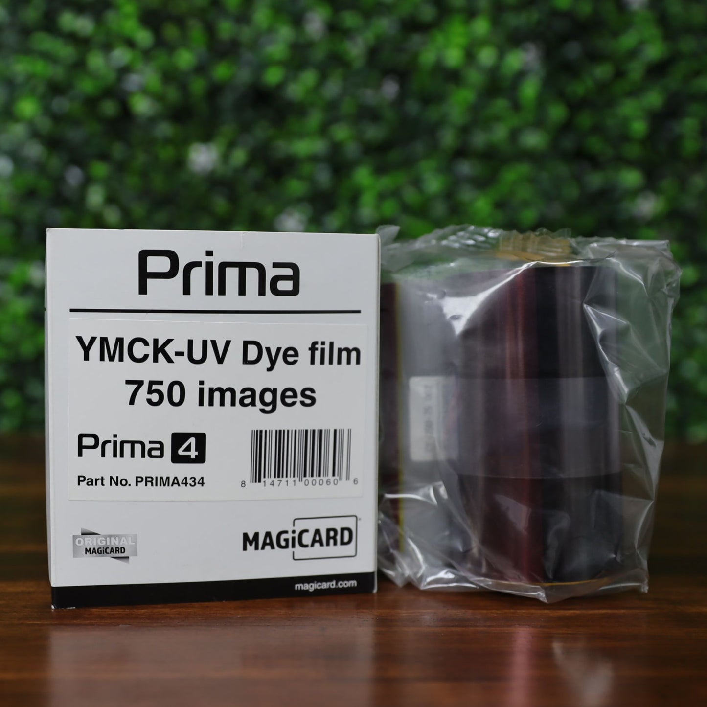 Front-facing view of the Magicard Prima434 YMCK-UV Ribbon packaging and ribbon roll. The box clearly shows the product title, part number (PRIMA434), and 750 image capacity. The ribbon is shown sealed in original plastic. Designed for Magicard Prima 4 series retransfer printers and used for producing high-security, full-color cards with an added UV layer. Photographed and sold by Specialist ID, an authorized Magicard dealer.