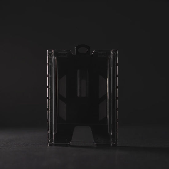 Product film of the black TEST-123 rigid vertical ID badge holder: the holder lit against a dark background, close-up detail on the metal spring belt clip and the Specialist ID name molded into the side rail, and the holder standing on a white background. Includes background music.