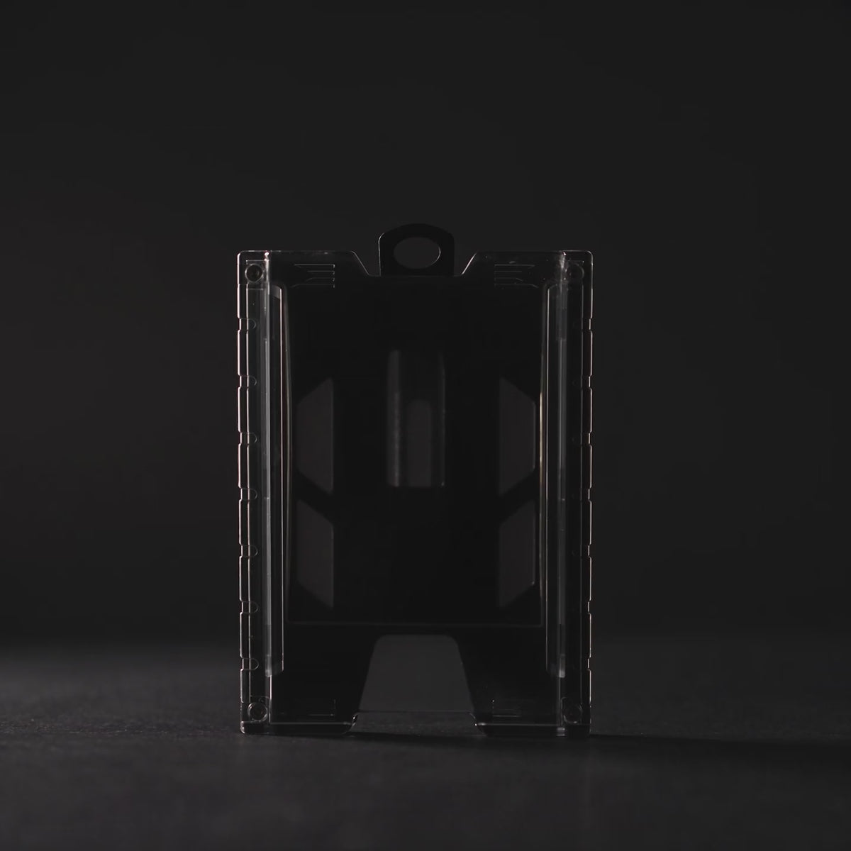 Product film of the black TEST-123 rigid vertical ID badge holder: the holder lit against a dark background, close-up detail on the metal spring belt clip and the Specialist ID name molded into the side rail, and the holder standing on a white background. Includes background music.