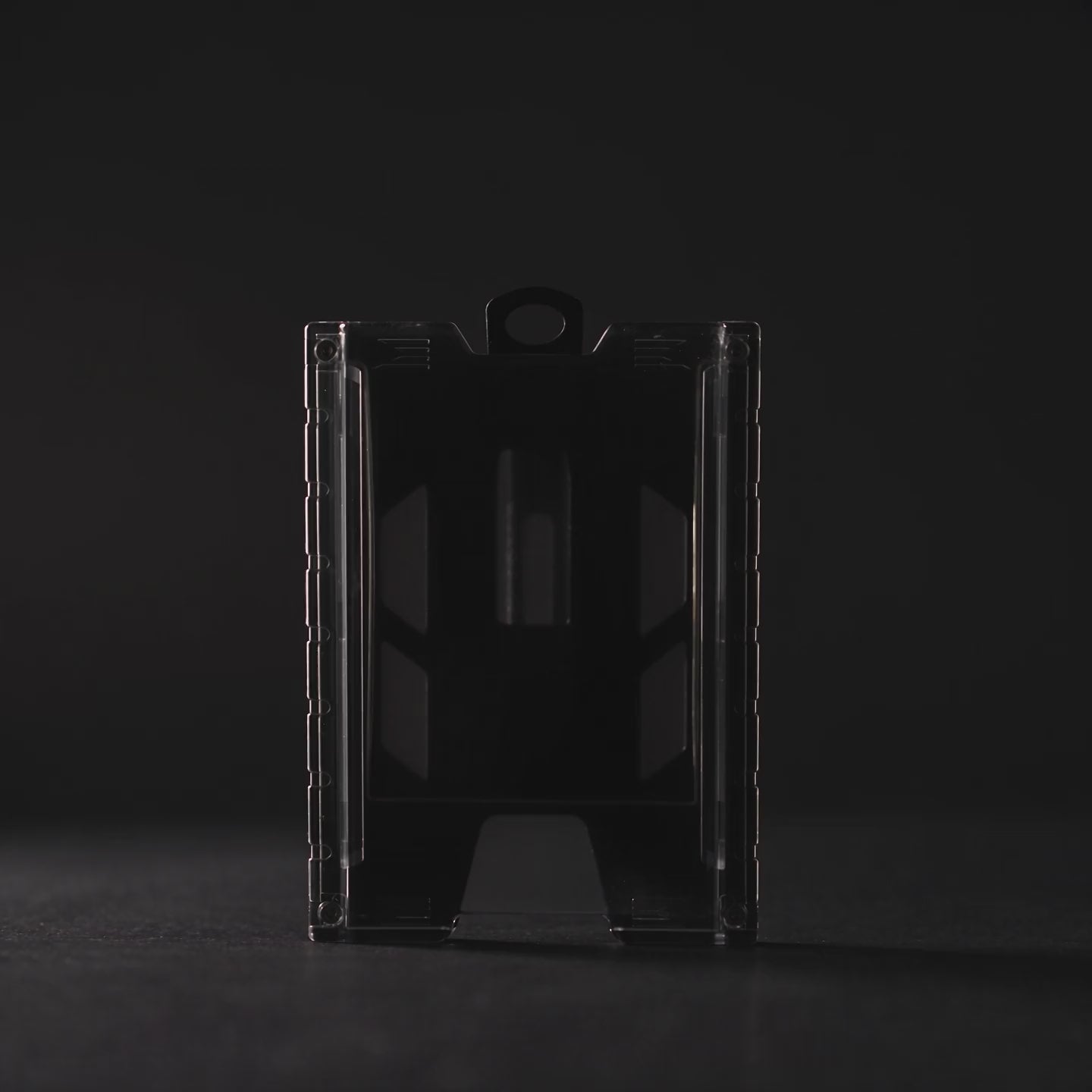 Product film of the black TEST-123 rigid vertical ID badge holder: the holder lit against a dark background, close-up detail on the metal spring belt clip and the Specialist ID name molded into the side rail, and the holder standing on a white background. Includes background music.