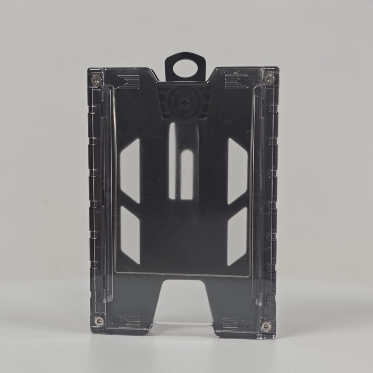 360-degree rotating view of the black TEST-123 rigid vertical ID badge holder, showing the clear front panel, the ribbed side rails, the molded top loop and the metal spring belt clip on the back.