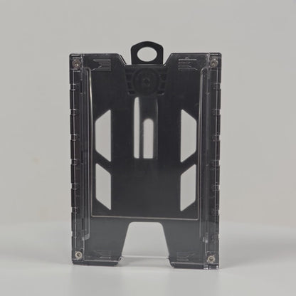 360-degree rotating view of the black TEST-123 rigid vertical ID badge holder, showing the clear front panel, the ribbed side rails, the molded top loop and the metal spring belt clip on the back.