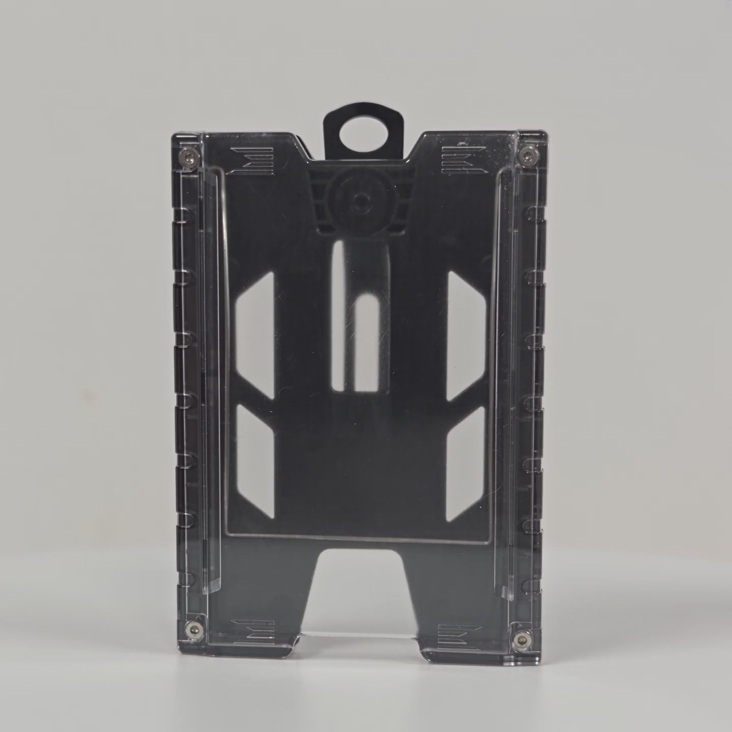360-degree rotating view of the black TEST-123 rigid vertical ID badge holder, showing the clear front panel, the ribbed side rails, the molded top loop and the metal spring belt clip on the back.