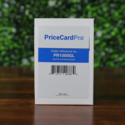 A Magicard PR1000GL Monochrome Gold Ribbon box for 1000 prints, compatible with PriceCardPro 100 and Flex+ ID Card Printers, sits on a wooden surface with a green blurred background. Photographed and sold by Specialist ID, an authorized Magicard dealer.