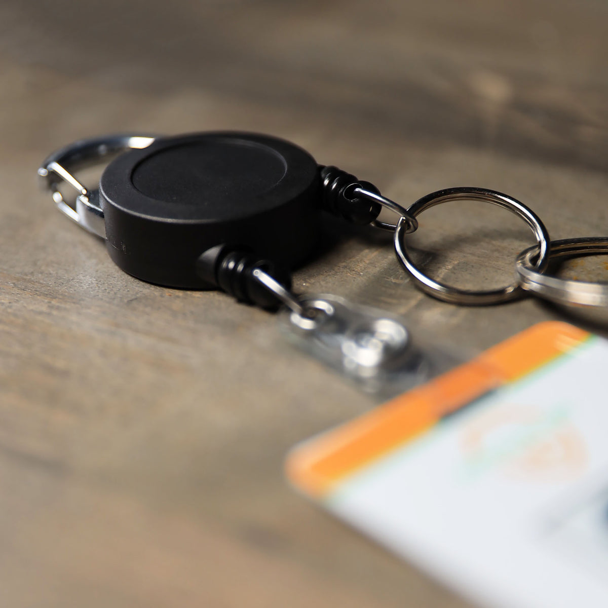 Dual badge reel lying on its side, one cord to a key ring and the other to a dual ID holder