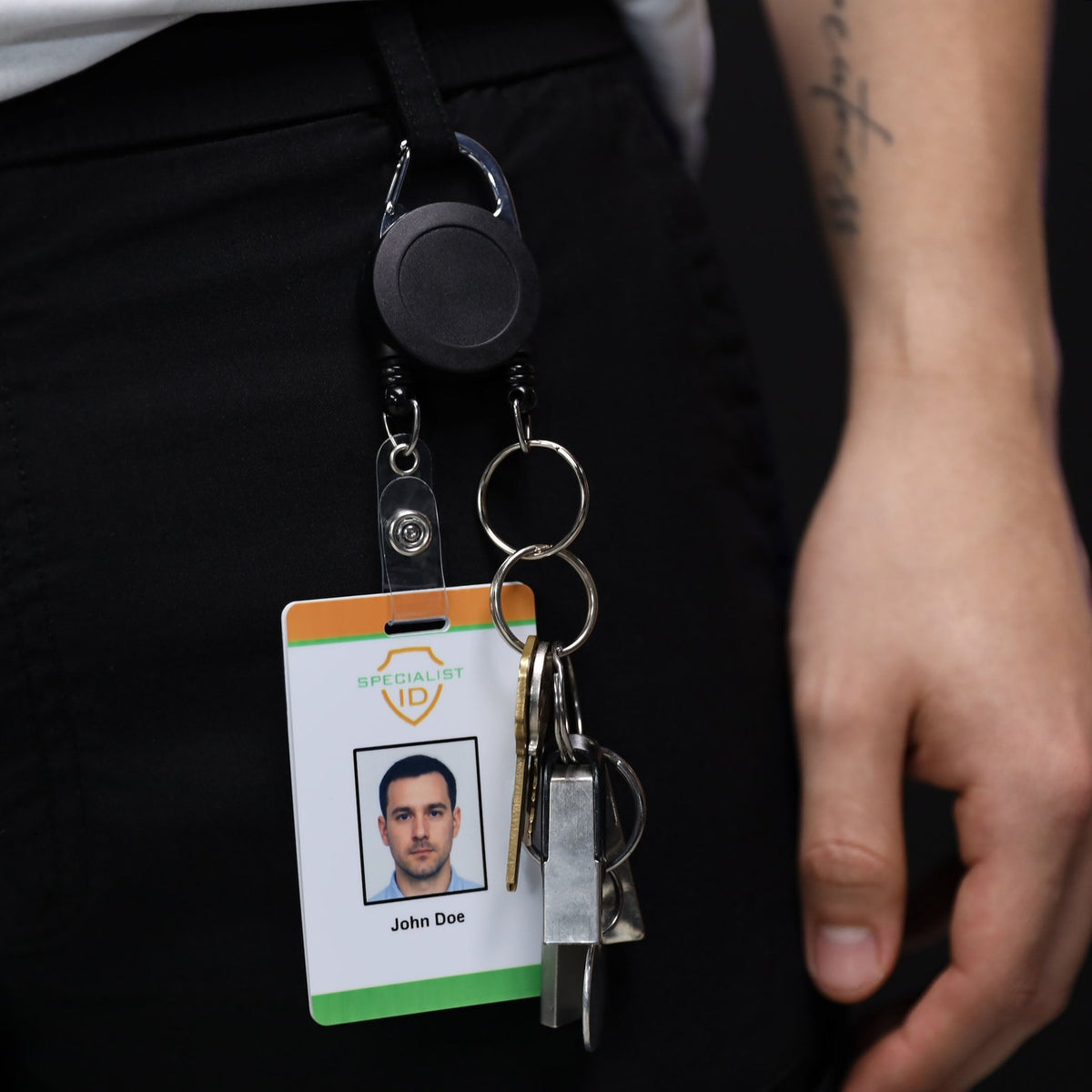 Dual carabiner badge reel clipped to a belt loop, holding an ID card and keys