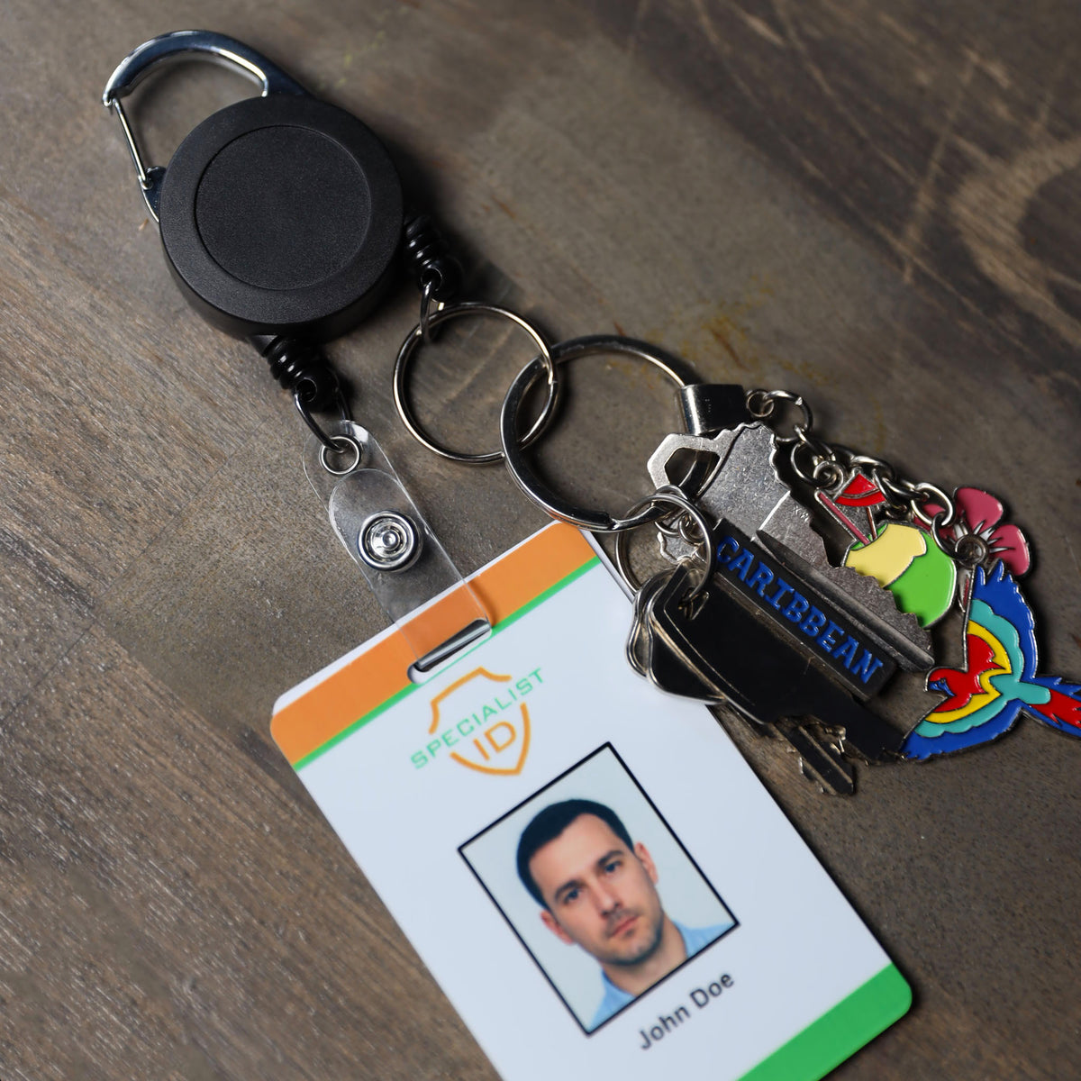 Dual badge reel on a wood surface with a name badge on one cord and keys and charms on the other