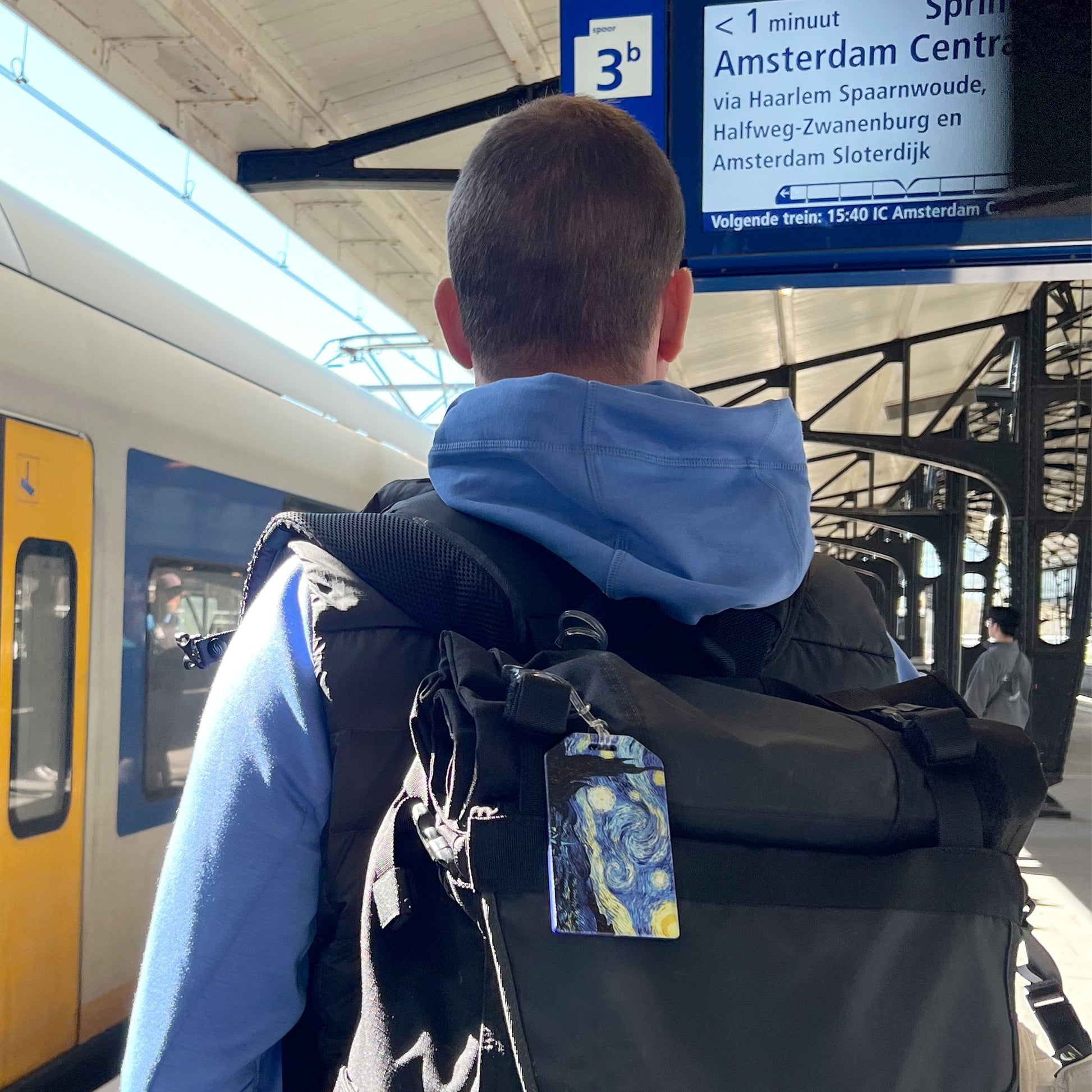 Starry Night luggage tag attached to a backpack during travel