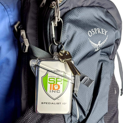 A close-up of a black Osprey backpack features a Witz See It Safe Waterproof ID Badge Holder (P/N 004) with a neck lanyard and a set of keys attached to it.