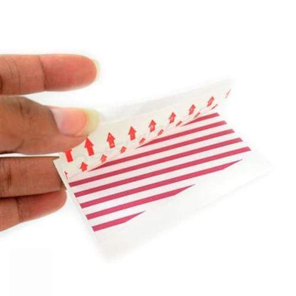 A close-up of a hand holding a piece of sticky tape with red arrows and lines indicating the direction for application, perfect for creating One Step Manually-Issued Self-Expiring Badges, Box of 500 (P/N T200X).