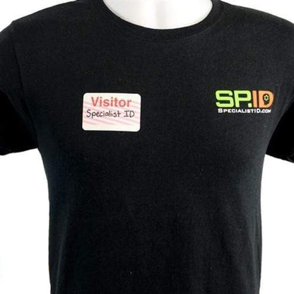 A person wearing a black t-shirt with a "Visitor Specialist ID" sticker featuring the "One Step Manually-Issued Self-Expiring Badges, Box of 500 (P/N T200X)" logo, showcasing efficient visitor identification.