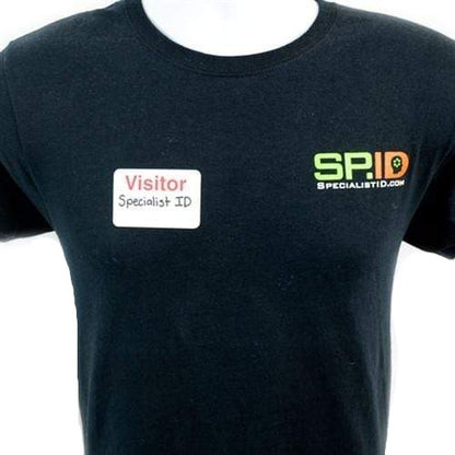 A person wearing a black t-shirt with a "Visitor Specialist ID" name tag on the left side and the "SpecialistID.com" logo on the right side, showcasing their One Step Manually-Issued Self-Expiring Badges, Box of 500 (P/N T200X).