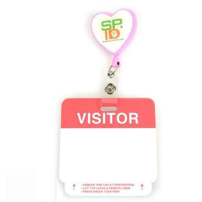 A red and white plastic badge holder with a heart-shaped clip, displaying the word "VISITOR" in bold letters at the top and a blank space below for customization. Ideal for those needing temporary visitor badges, this 500 Pack - Self Expiring Visitor Temp Badges (P/N T2014) combines convenience and charm.