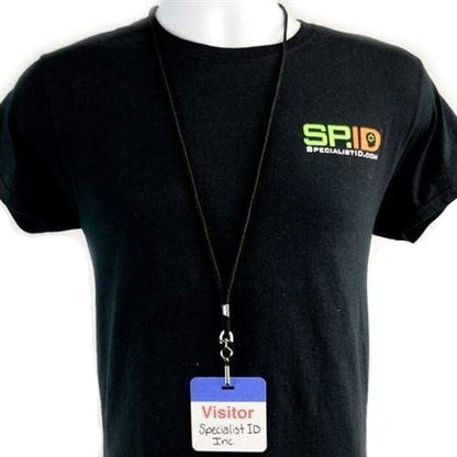 A person is wearing a black Specialist ID Inc. T-shirt with a Self Expiring Clip-on Backpart, Box of 1,000 (P/N T590X) on a lanyard hanging around their neck, demonstrating an efficient visitor management process.