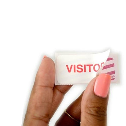 A hand with pink nail polish peels off a white visitor sticker with red text, revealing a One-day TIMEtoken Backpart Indicator, Box of 1000 (P/N T6057) for efficient visitor management.